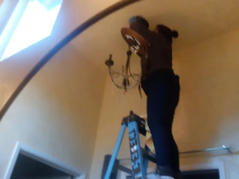Electrician installing a chandelier in a Ramsey residence